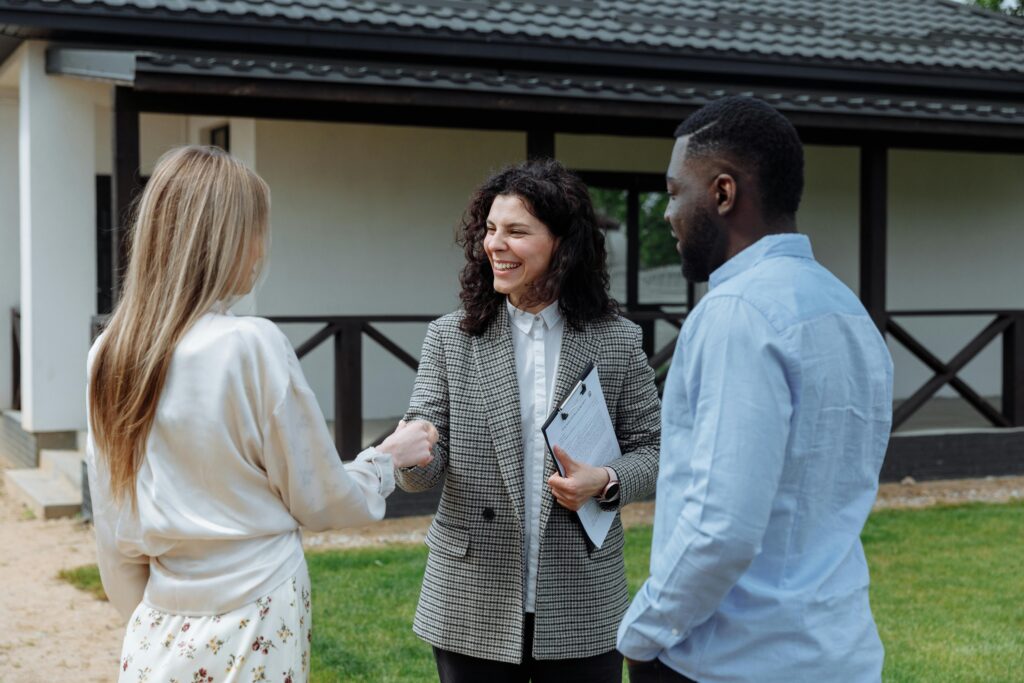 pexels-photo-8469941-8469941 A real estate agent shakes hands with a couple outside a modern house, symbolizing a successful property deal.